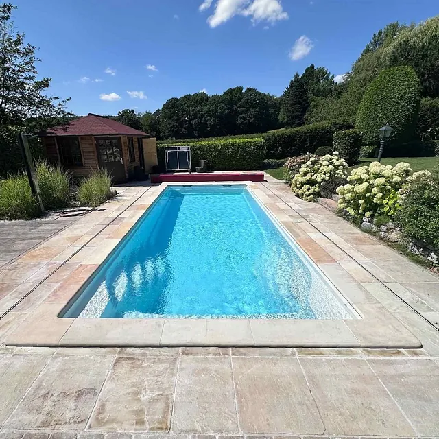 Pool mit Sitzecke daneben und modernen Poolhaus im Hintergrund